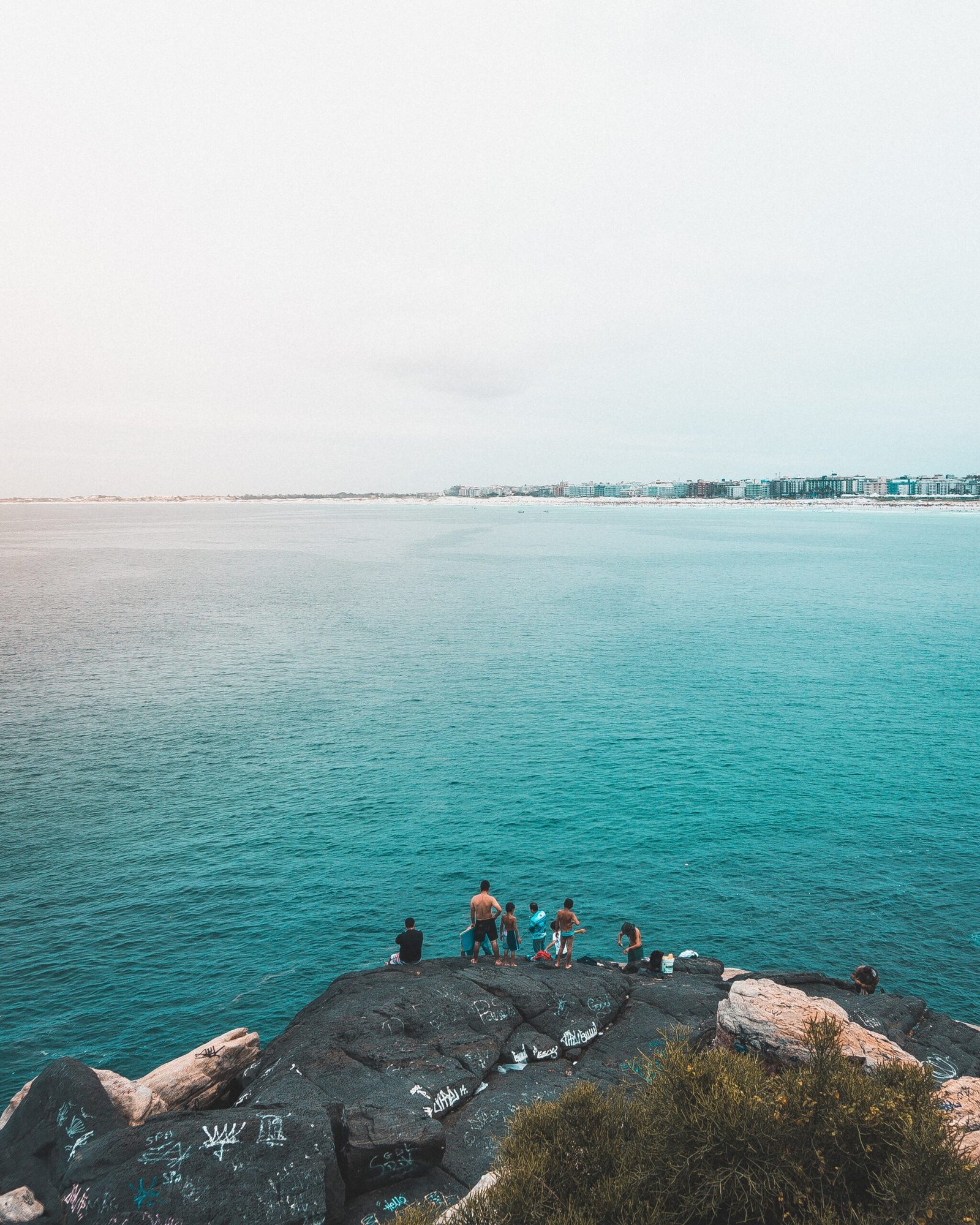 A vertical shot of fishers fishing in the blue sea in Rio de Janeiro